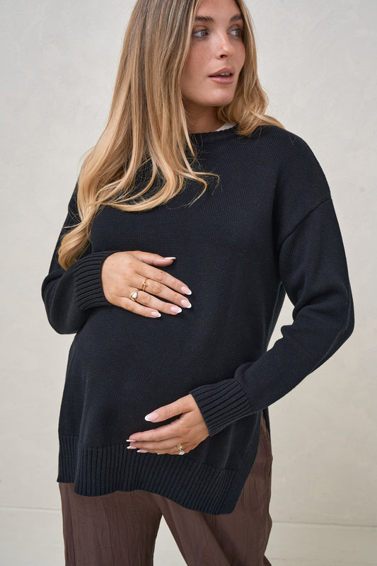 Pregnant model wearing relaxed black maternity knit sweater