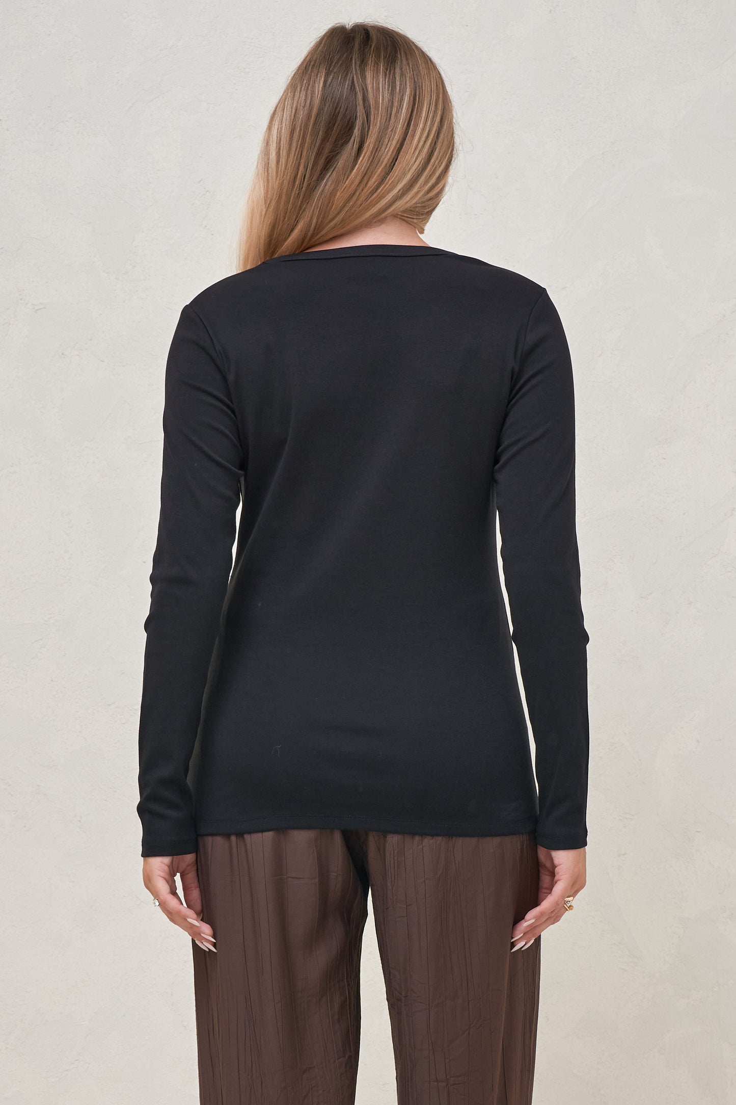 Back view of a long sleeve maternity top worn out over brown pants