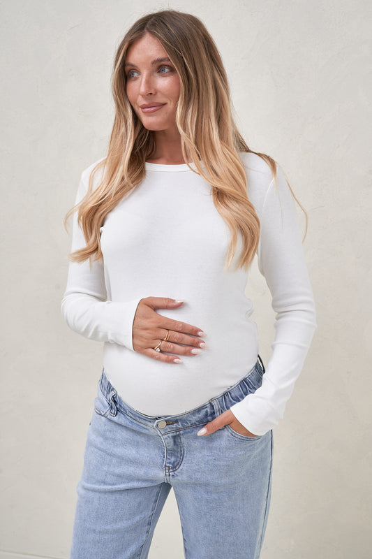 Pregnant model wearing a white long sleeve top tucked into light blue maternity jeans