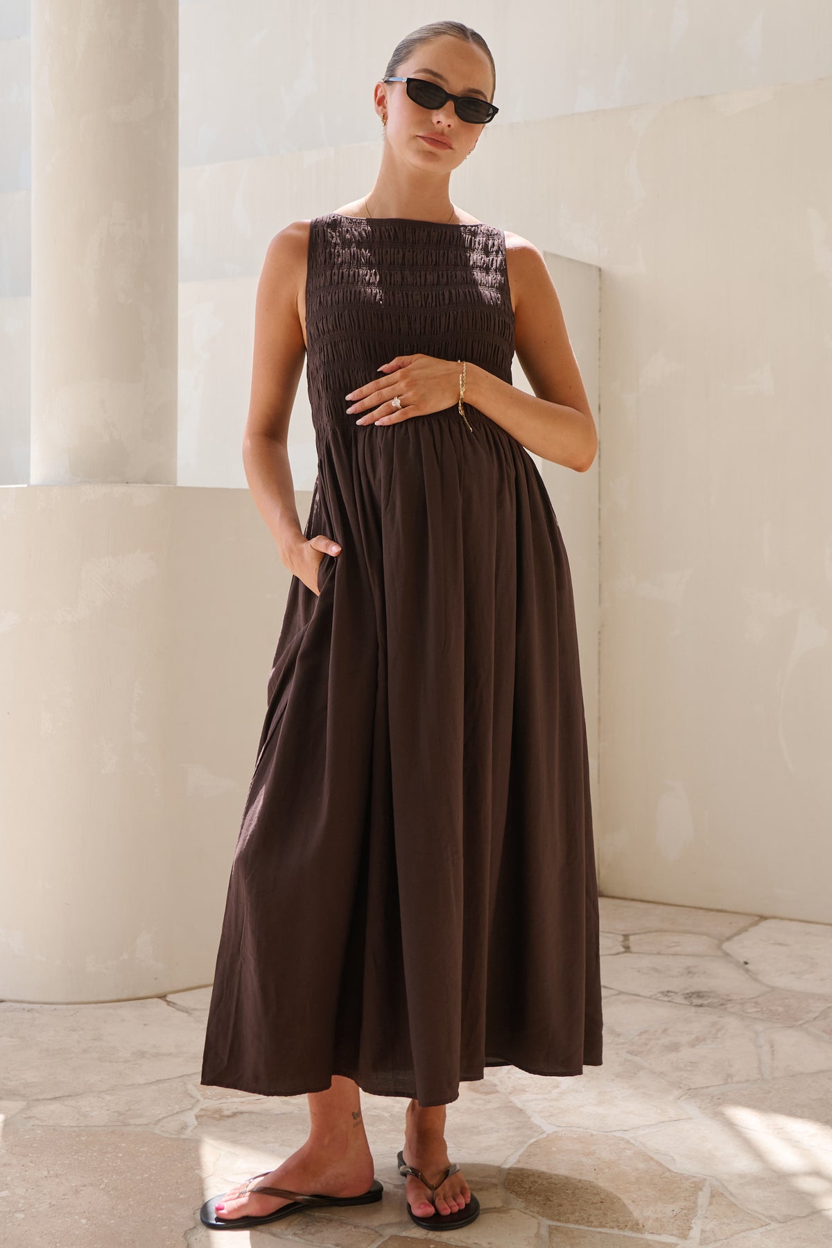 Maternity maxi dress in brown – front view with hand on bump and hand in side pocket