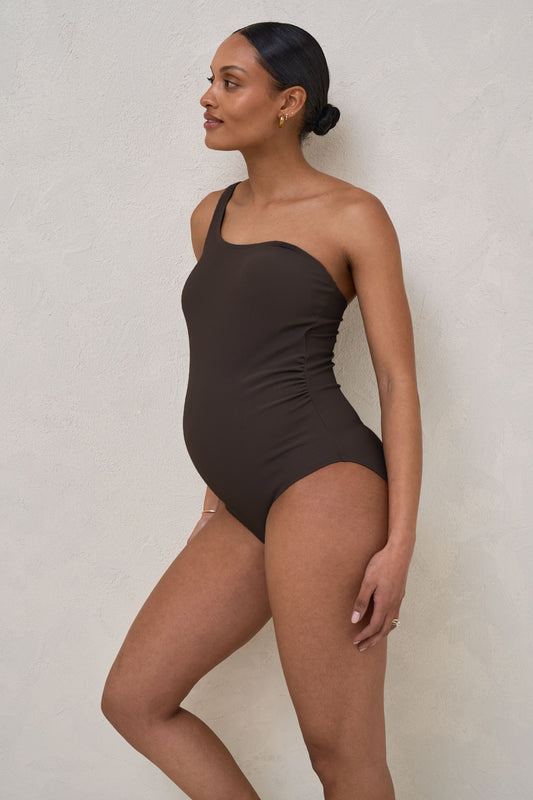Side profile of pregnant woman wearing chocolate maternity rib one piece swimsuit