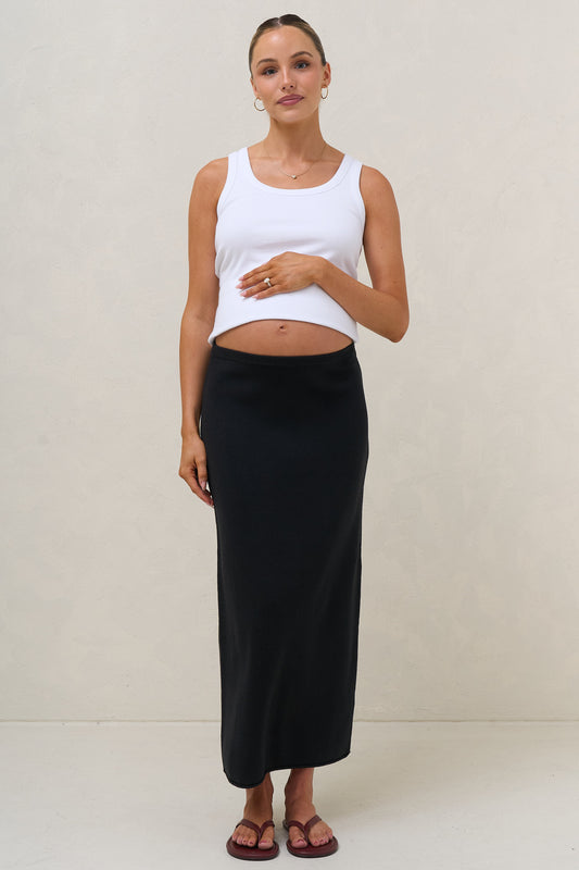 Maternity knit midi skirt in black – front view worn under bump with white crop top