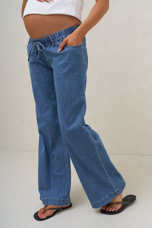 Wide leg maternity jeans in blue – front view with hands in pockets